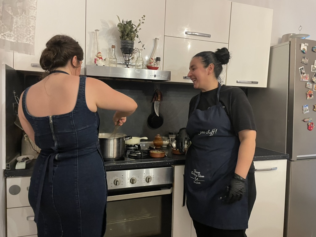 Tirana Cooking Class - Sindi at the stove helping a student stir a pot