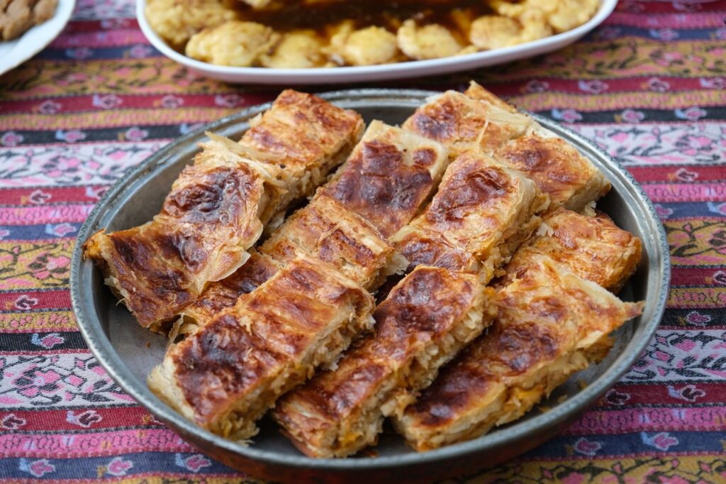 Delicious tray of Turkish Börek served on a vibrant traditional tablecloth. Tempting pastry for cultural food lovers.